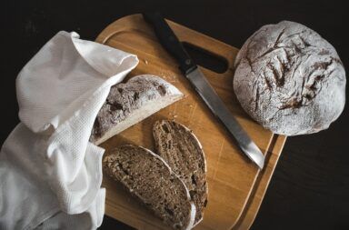 nóż i pokrojony bochenek chleba na desce